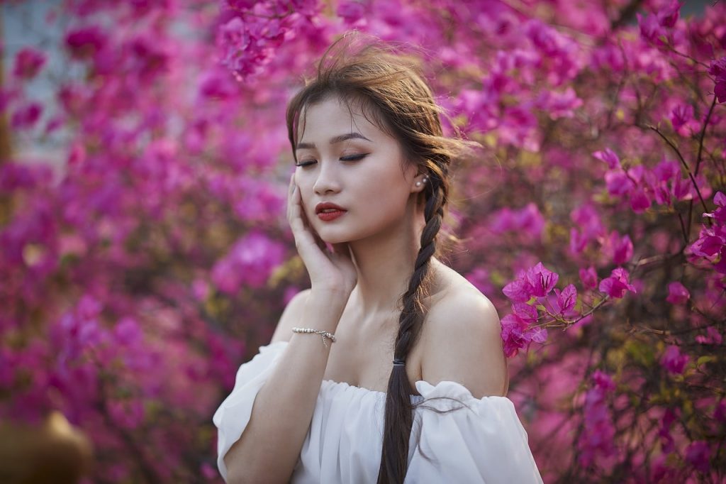 目を閉じて頬に手を当てる女性