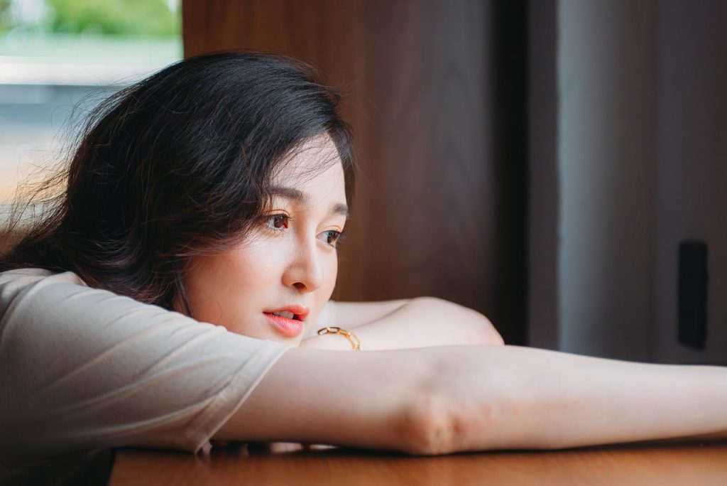 女性が窓際で考えてごとをしている